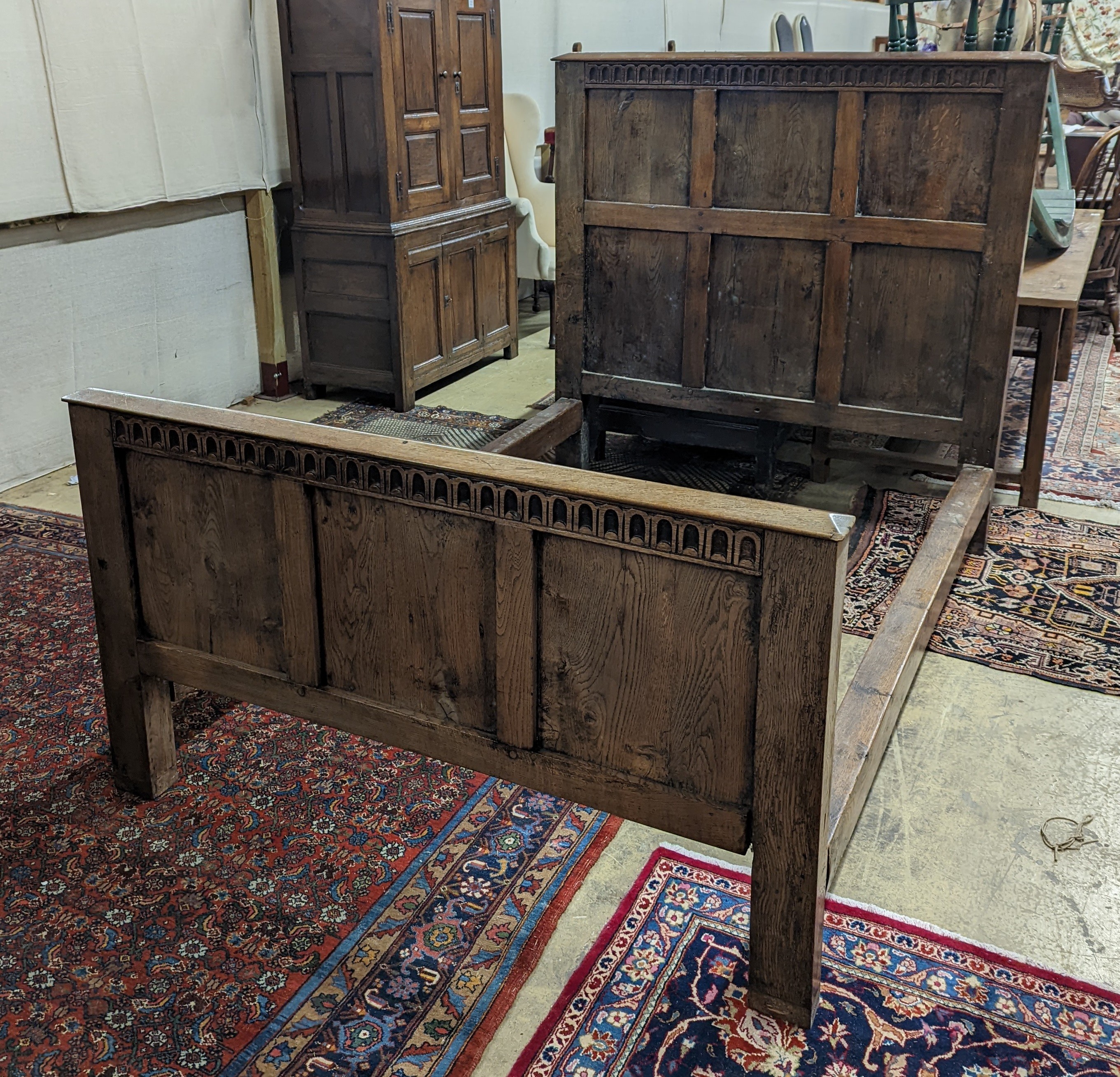 A 17th century style panelled oak bedstead, width 143cm, length 204cm, height 140cm